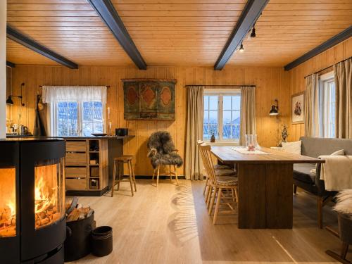 a living room with a fireplace and a table and chairs at Charming Cabin Near Hallingskarvet Ski Center, Cozy and Inviting! in Skoro