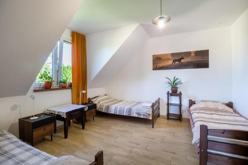 a attic room with two beds and a table at Dolistówka Apartamenty z jacuzzi i sauną in Goniadz