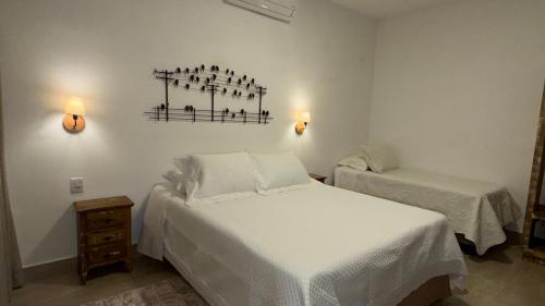 a bedroom with two beds and two lights on the wall at Pousada Pouso de Laura in Tiradentes