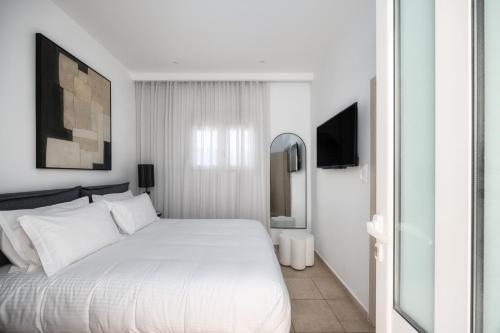 a white bedroom with a white bed and a mirror at Ierapetra’s Mosque House in Ierapetra