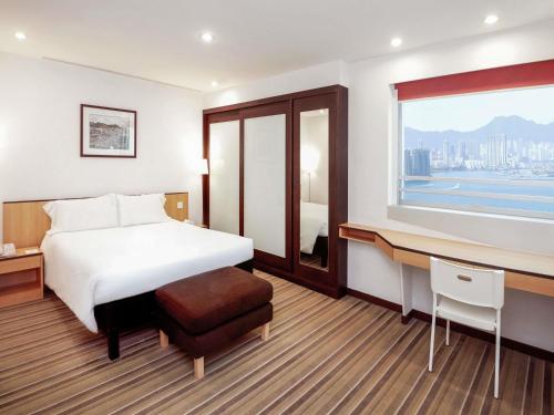 a hotel room with a bed and a desk and a window at ibis Hong Kong North Point in Hong Kong