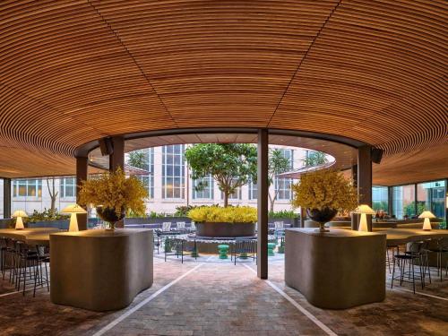a restaurant with tables and chairs and a wooden ceiling at Sofitel Sydney Wentworth in Sydney