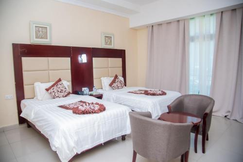 a hotel room with two beds and a chair at Mika Convention Center in Lusaka