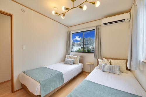 two beds in a room with a window at 北谷町港1 in Chatan
