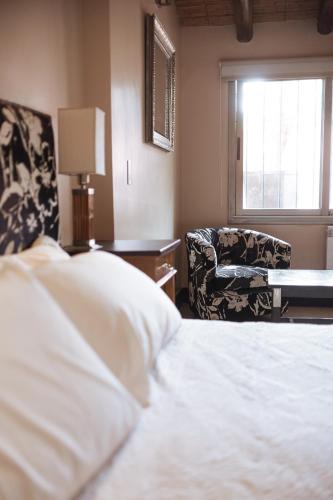 a bedroom with a bed and a chair and a window at Casa Entonada - Hotel Boutique in Chacras de Coria