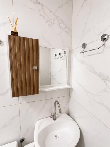 a white bathroom with a sink and a mirror at Manaira Suite 02 in João Pessoa
