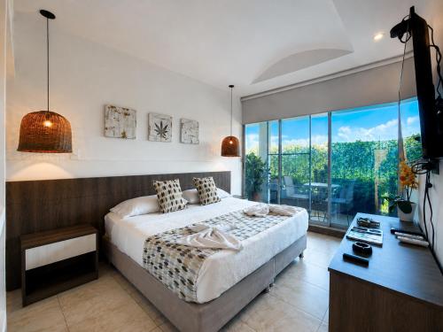 a bedroom with a bed and a desk and a window at Hotel Four20 Zensi - Meta in Lejanías