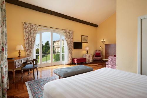 a bedroom with a bed and a desk and a window at Sina Villa Matilde in Romano Canavese