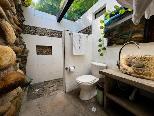 a bathroom with a toilet and a stone wall at Hotel Four20 Zensi - Meta in Lejanías