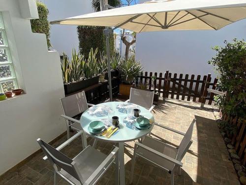 a table and chairs with an umbrella on a patio at PLAYMAR Refugio Palmeras in Maspalomas