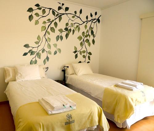 two beds in a room with a tree mural on the wall at Herdade do Burrazeiro Turismo Rural no Alentejo in Borba