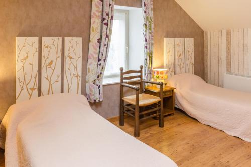 a bedroom with two beds and a chair and a window at La clémenceraie in Baroville