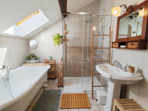 a bathroom with a tub and a sink and a shower at La clémenceraie in Baroville