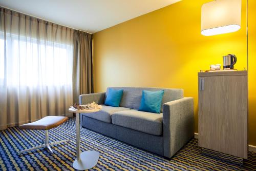 a living room with a couch and a table at Mercure Paris Sud Les Ulis-Courtaboeuf in Les Ulis