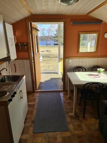 a kitchen and dining room with a table and a door at Sommens Camping in Sommen