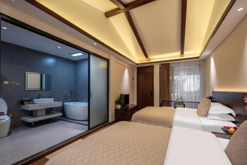 a bedroom with a bed and a bathroom with a tub at 木老爷客栈 in Lijiang
