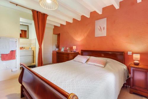 a bedroom with a large bed and an orange wall at Le Duzon avec Piscine in Saint-Sylvestre