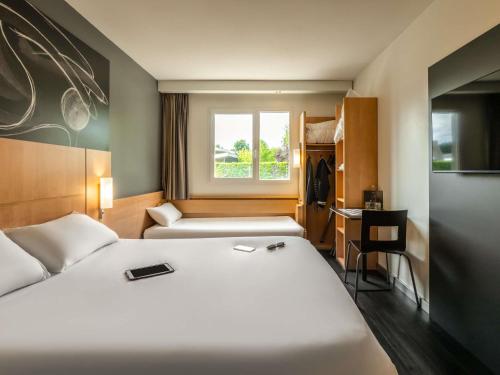 a bedroom with a bed and a desk and a window at ibis Issoire in Issoire