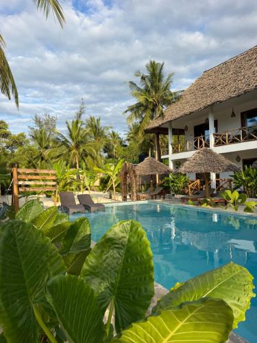 a resort with a swimming pool and palm trees at Pamoja Villas in Migogoni