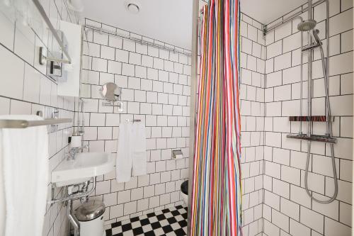 a bathroom with a sink and a striped shower curtain at Hotell Hanöbris på Kivik in Kivik