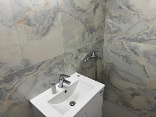 a bathroom with a white sink and a marble wall at Arolen in Nesebar