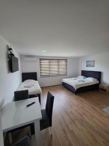 a room with two beds and a table and chairs at Apartmani gradina Tuzla in Tuzla