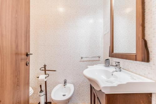 a white bathroom with a sink and a mirror at Le Terre Di BAC in Borgo Montenero