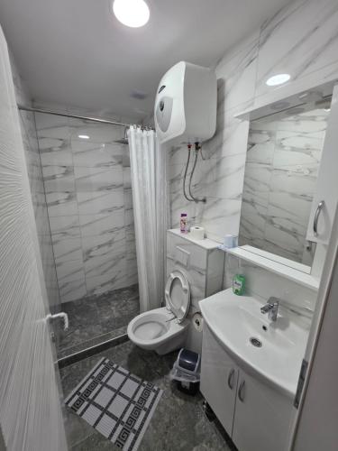a white bathroom with a toilet and a sink at Apartmani gradina Tuzla in Tuzla