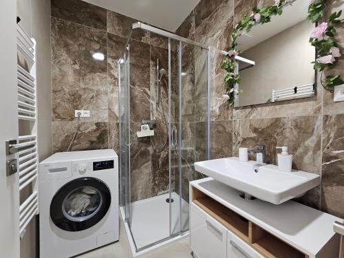 a bathroom with a washing machine and a sink at Apartmán Meridiem Komárovská in Komárov