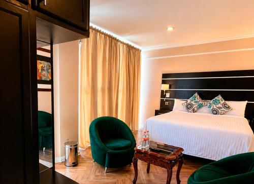 a bedroom with a bed and a green chair at Hotel Cacaxtla Collection in Tlaxcala de Xicohténcatl