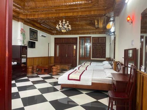 a bedroom with a large bed and a checkered floor at Hottel ANH LONG in Buôn Ðũng