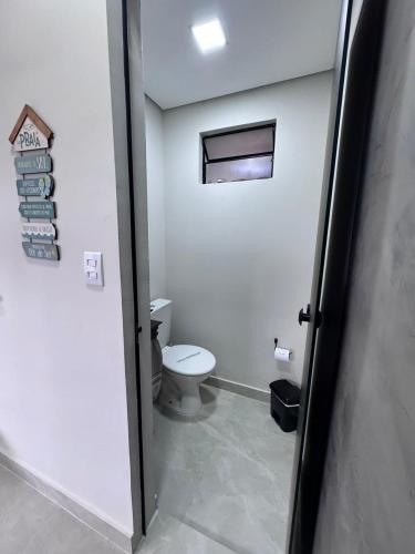 a bathroom with a toilet and a window and a door at Sobrados Novos Litoral Norte Caraguatatuba, a 150 m a pe da Praia das Palmeiras, Ar condicionado, WiFi gratis, Churrasqueira privativa, Pet friendly, Estacionamento in Caraguatatuba