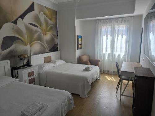 a bedroom with two beds and a table and a desk at Hostal La Mexicana in Santander
