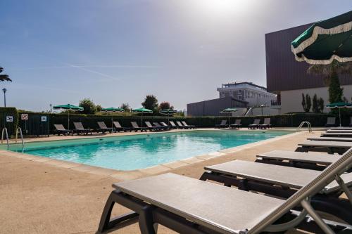 a swimming pool with lounge chairs and a building at Résidence Pierre & Vacances L'Archipel in Perros-Guirec