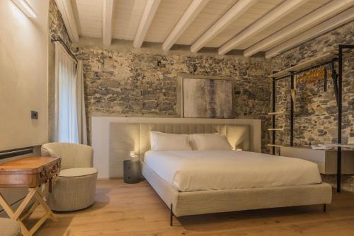 a bedroom with a bed and a stone wall at La Corte del Lario - Contrada dei Sarti in Varenna