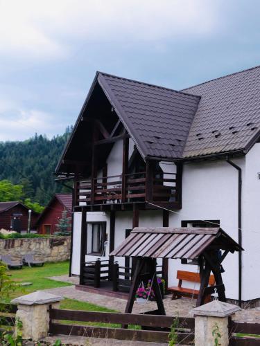 a white house with a black roof and a playground at Olko House in Yaremche