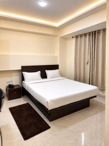 a bedroom with a large bed with white sheets at The Bliss Hotel and Restaurant in Gangtok