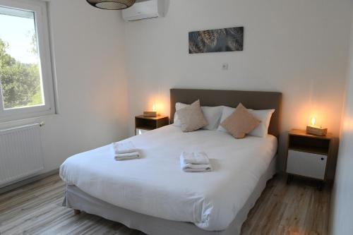 a bedroom with a white bed with two towels on it at Domaine familial, Le Parc de Gouts in Aiguillon