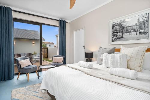 a bedroom with a large white bed and a patio at 8 on Nivenia in Bettyʼs Bay