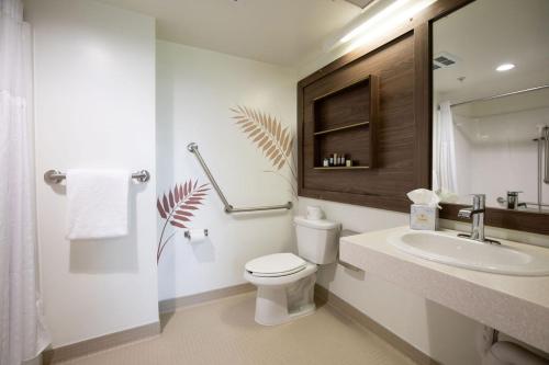 a white bathroom with a toilet and a sink at Hotel Burnaby in Burnaby