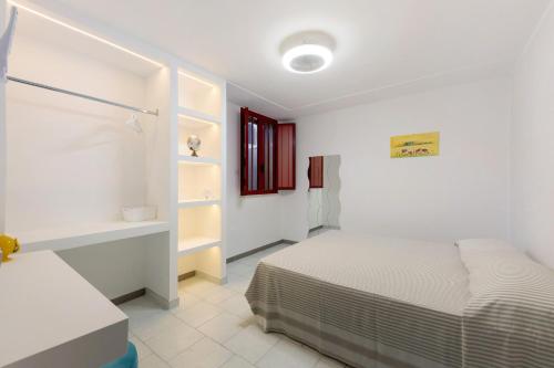 a white bedroom with a bed and a window at cmv Salento in Marina di Pescoluse