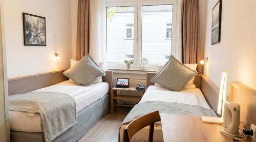 a hotel room with two beds and a window at Stadt-gut-Hotel Rheinischer Hof in Essen