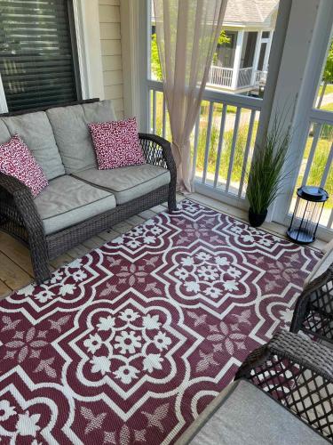 a living room with a couch and a rug on a porch at The Phoebe - 65 Butternut in Cherry Valley