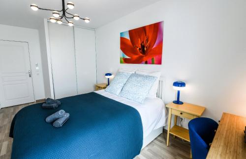 a bedroom with a blue bed and a painting on the wall at T2 Cocon Prestige Lyonnais : Sécurité Commodités in Vénissieux