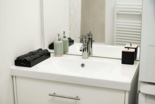 a white bathroom with a sink and a mirror at T2 Cocon Prestige Lyonnais : Sécurité Commodités in Vénissieux
