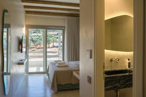 a bedroom with a bed and a bathroom with a sink at Lithos Luxury Suites in Tinos