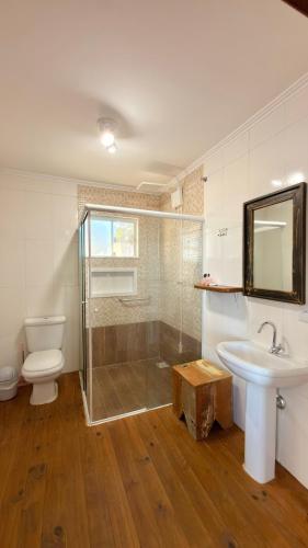 a bathroom with a toilet a sink and a shower at Pousada Farol do Rosa in Praia do Rosa