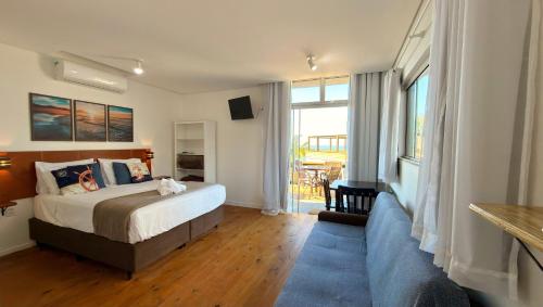 a bedroom with a bed and a large window at Pousada Farol do Rosa in Praia do Rosa