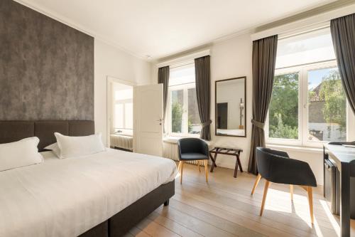 a hotel room with a bed and a desk and chairs at B&B Huyze Weyne in Bruges
