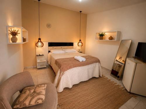 a bedroom with a large bed and a chair at Bru&Mar Pousada in Parnaíba